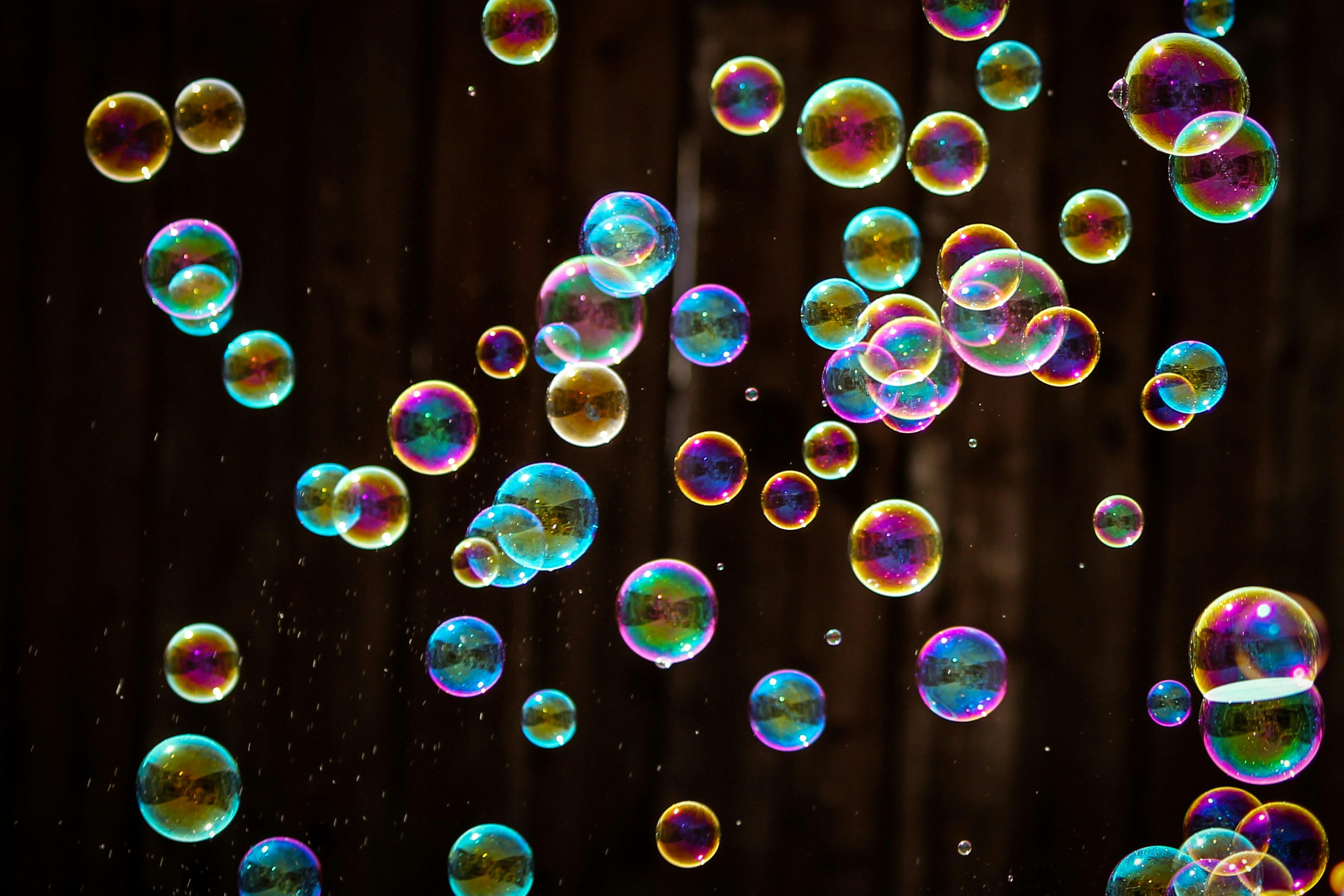 Image of many bubbles that appear to be multicolored against a dark background.