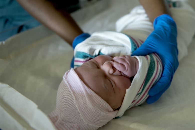 Image of a newborn baby being handled by a nurse. 