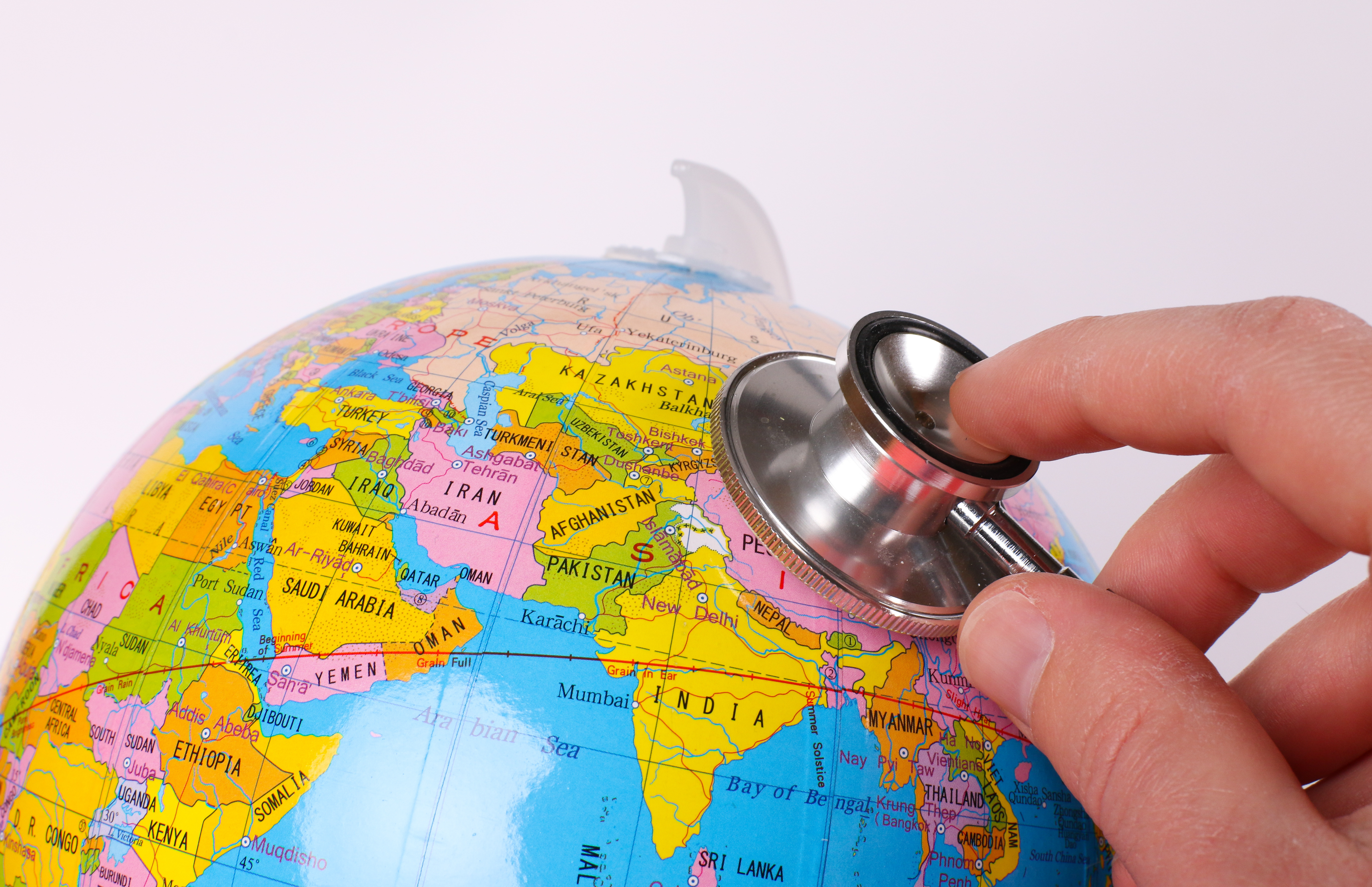 Hand holding stethoscope on colorful globe
