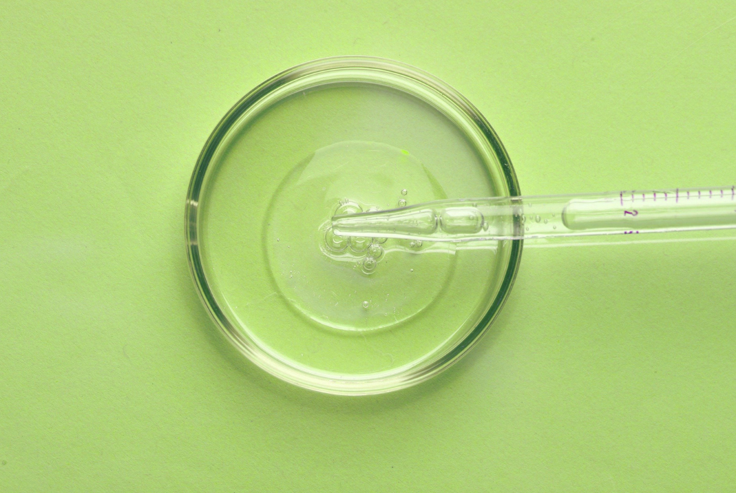 Petri dish and dropper on green background