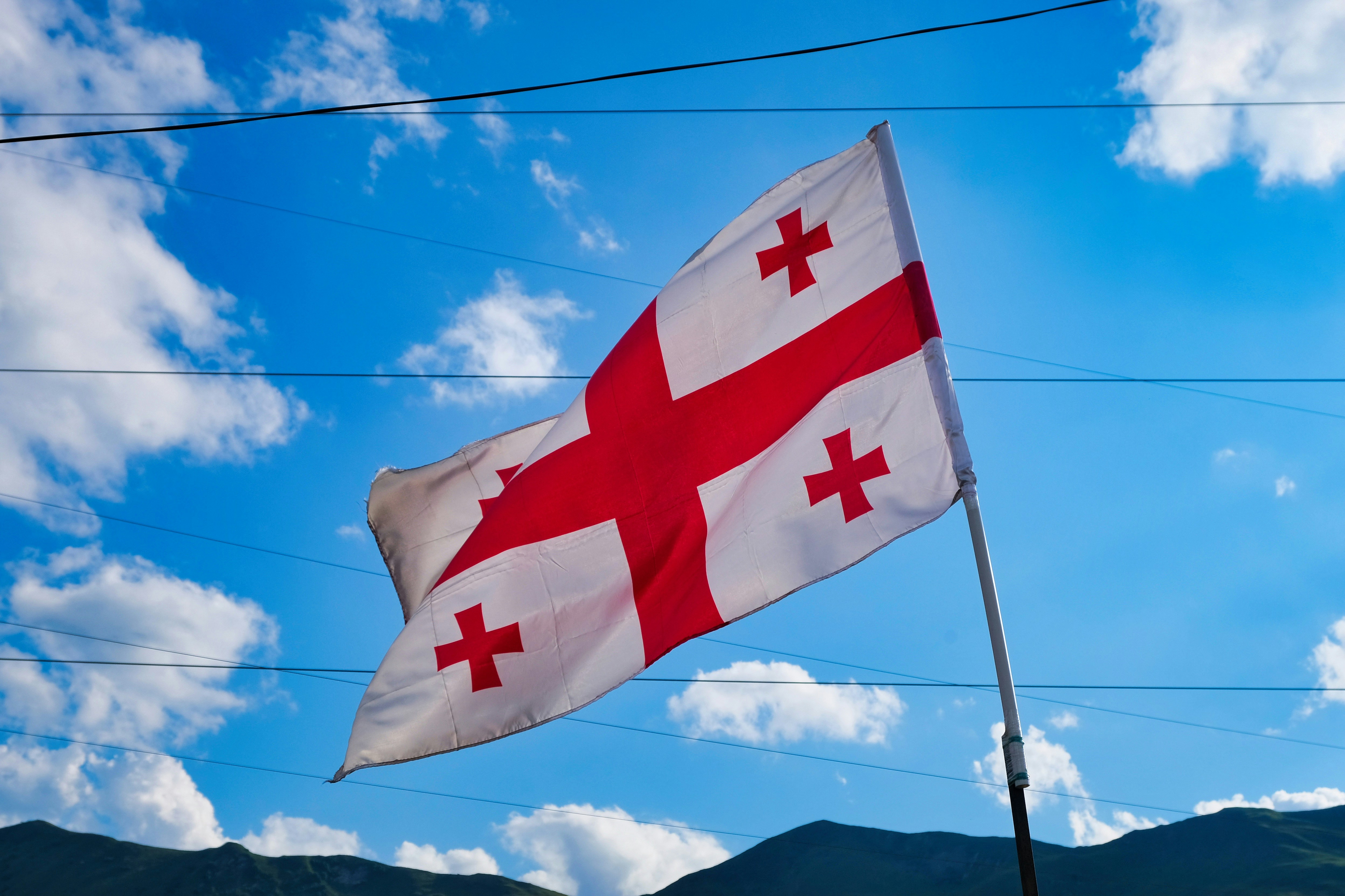 Georgian flag against a blue sky with clouds