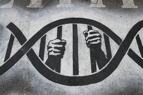 Street art illustrating a double helix. In between there appears human hands as if imprisoned by the strands.