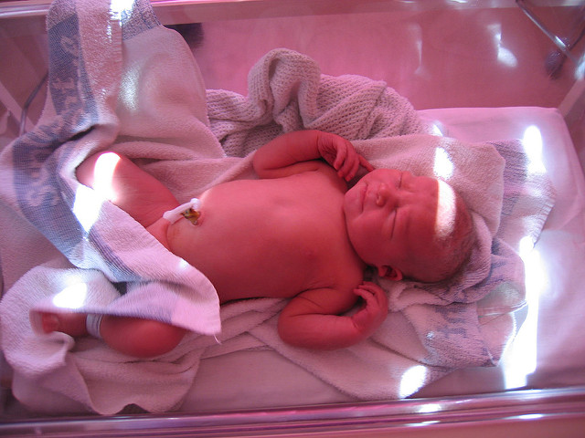 A newborn baby lays in a  hospital crib
