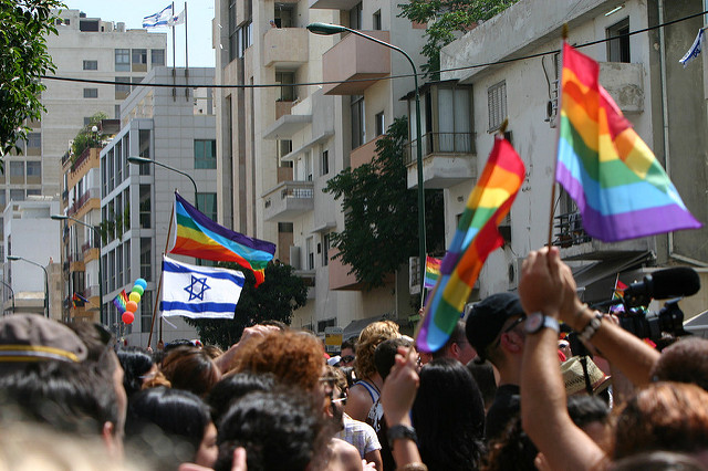 Image of goup of people waving pride flag and Israeli flag.