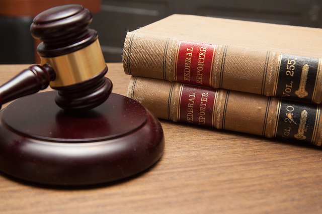 On a desk lies a judge's wooden gavel, and two books.