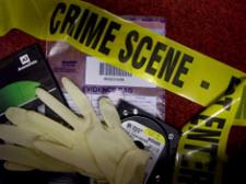 Crime scene tape, gloves, and packages of evidence are stacked in a pile on a desk.