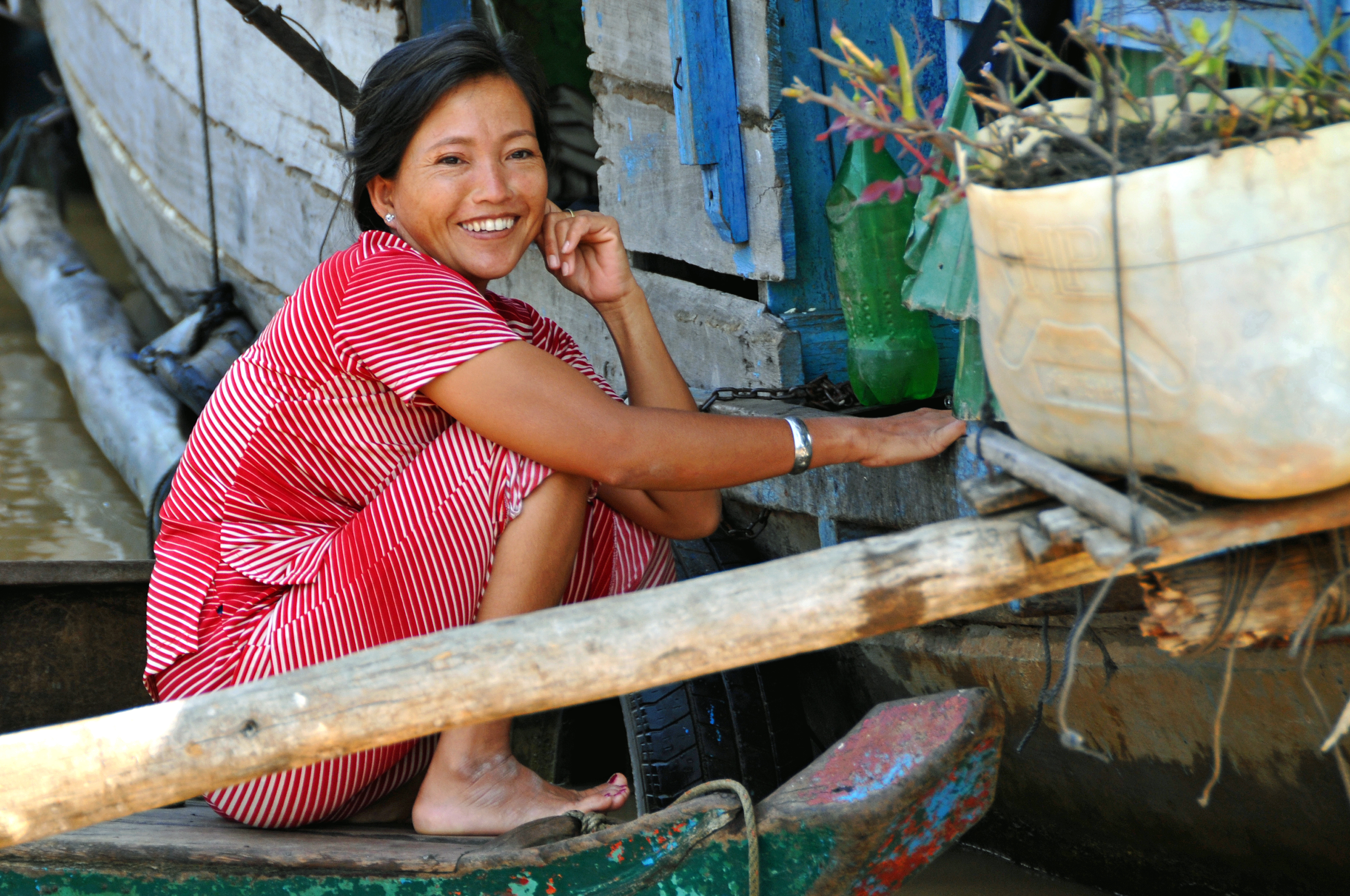 Portrait photo of a Cambodian woman smiling, while sitting on the ground.