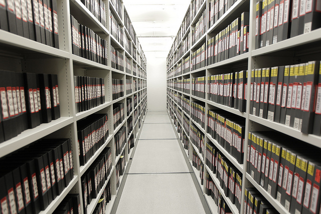 Image of an aisle in a storage hacility with binders/boxes of numbered material.