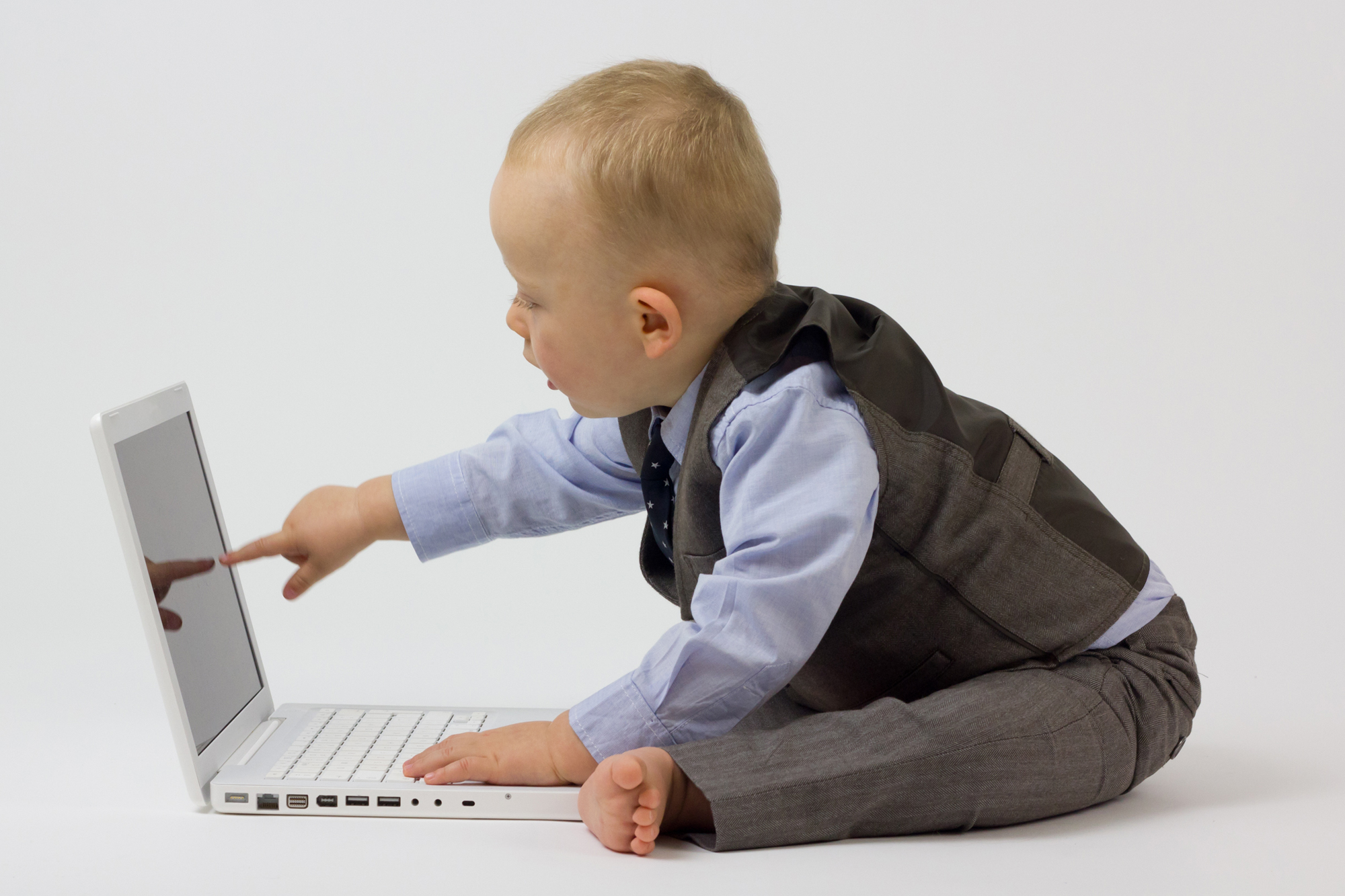 A white baby in a business suit, leans in and points at a laptop screen.