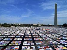 The enormous AIDS memorial quilt is colorfully laid on the ground, with the Washington Monument standing in the background.