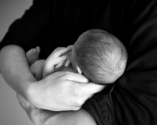 lack and white photo of an adult holding a baby in their arms.