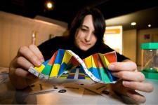 An individual holds a DNA model, with a concentrated face as if studying it.