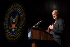 Director of National Intelligence James R. Clapper stands at a podium as a speaker, with the Office of Director of National Intelligence symbol in the background.