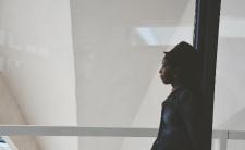 a person of African descent standing against a pole