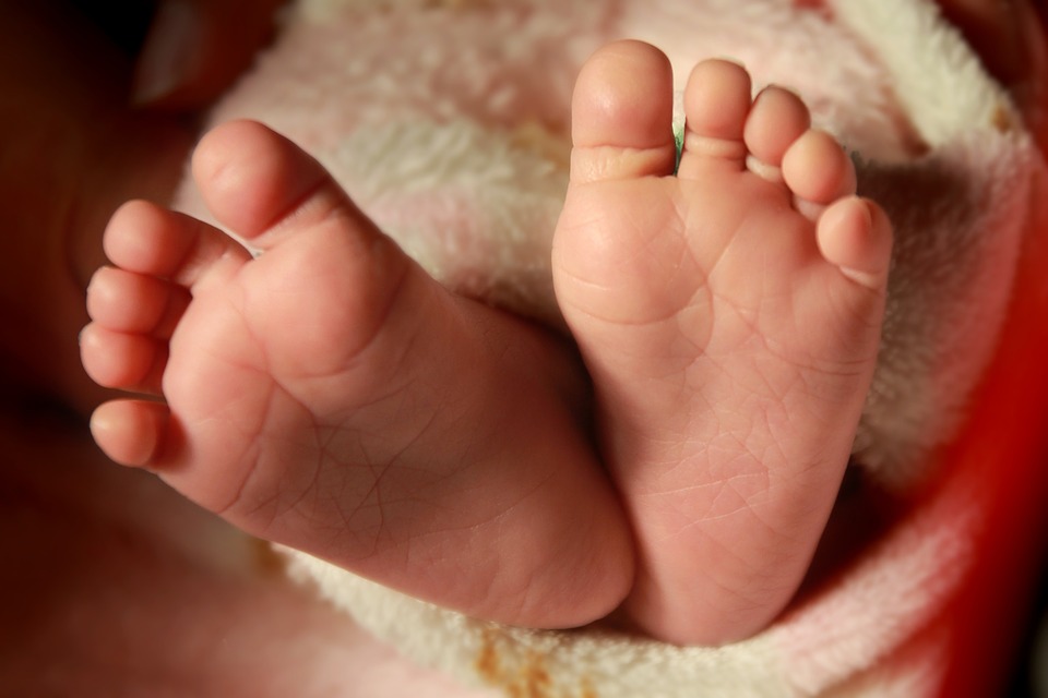 2 small baby feet wrapped in a cream colored blanket