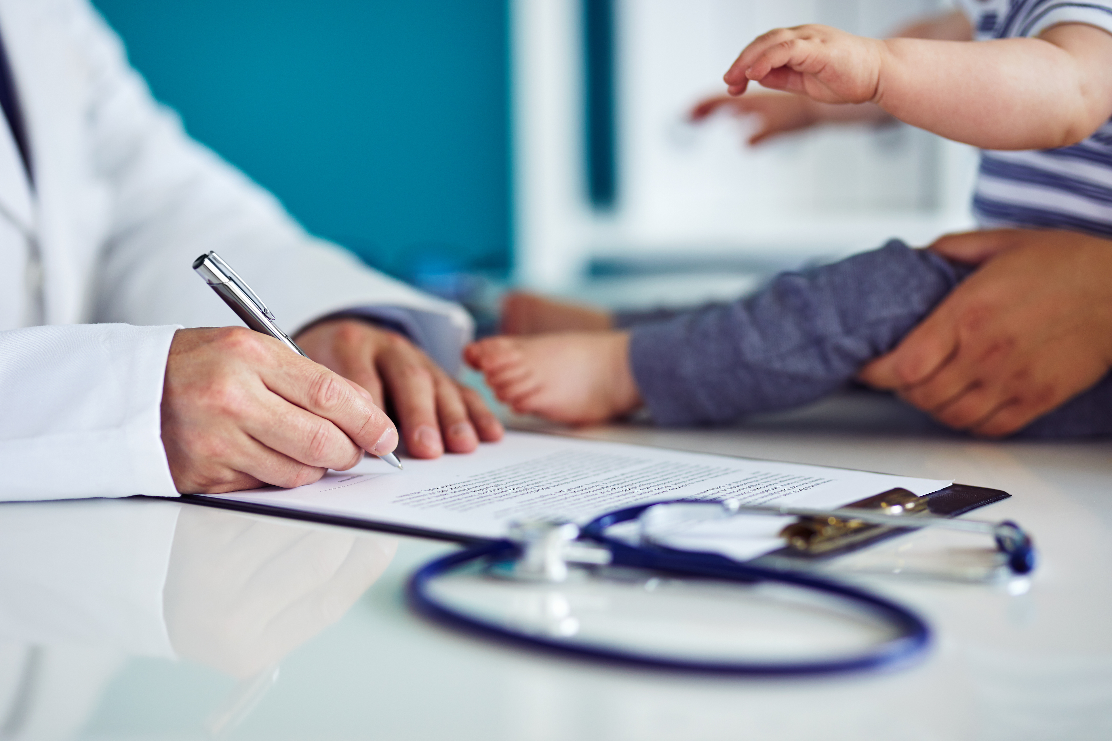 doctor makes notes on a baby with stethoscope in the foreground