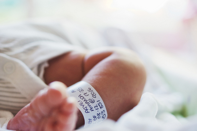 Close up of a baby's foot, when lying down, with a hospital tag attached to their ankle.