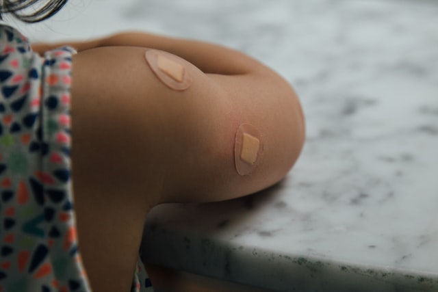 the arm of a child with two small bandaids on it