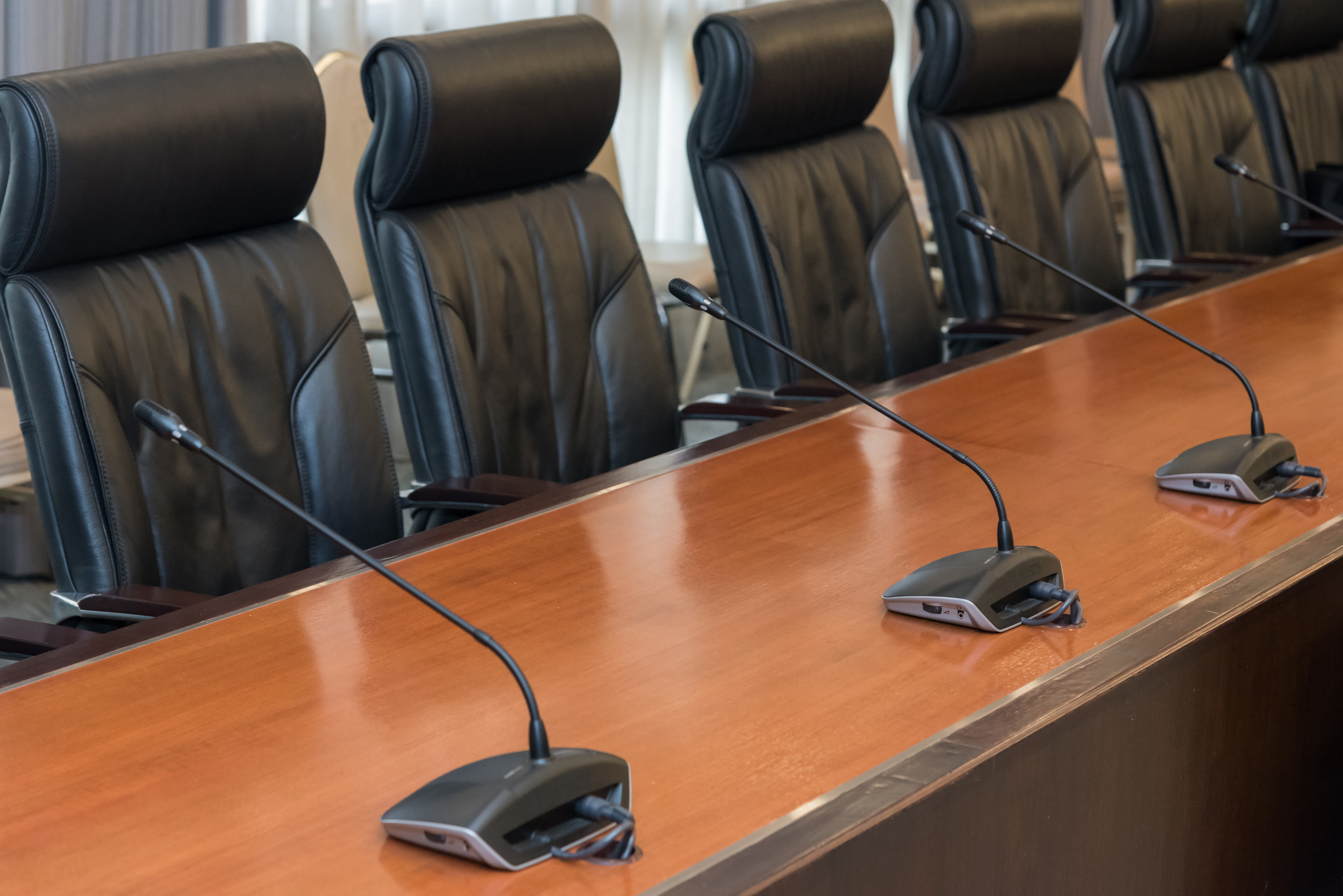 Empty chairs at a board room table with microphones
