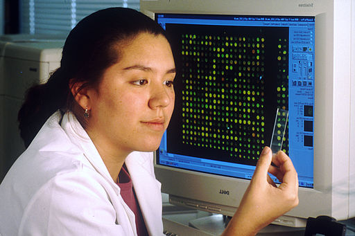 Female laboratory technician sitting at computer that displays a DNA microarray