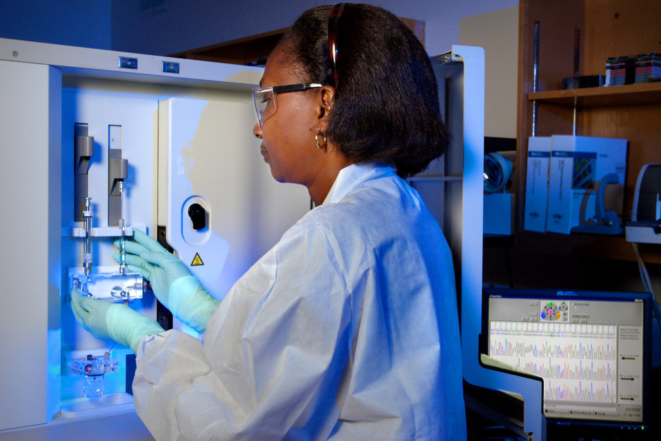 Woman in lab coat looking at test tubes