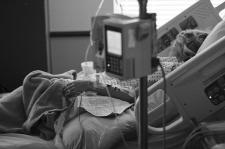Black and white photo of a woman laying in a hospital bed.