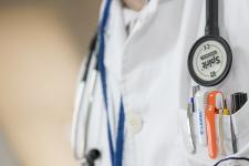 Doctor in white coat, with stethoscope and pens in pockets.