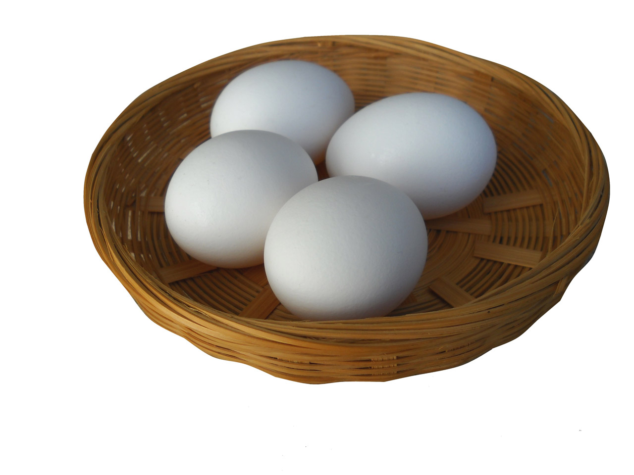 Four eggs in a shallow wicker basket