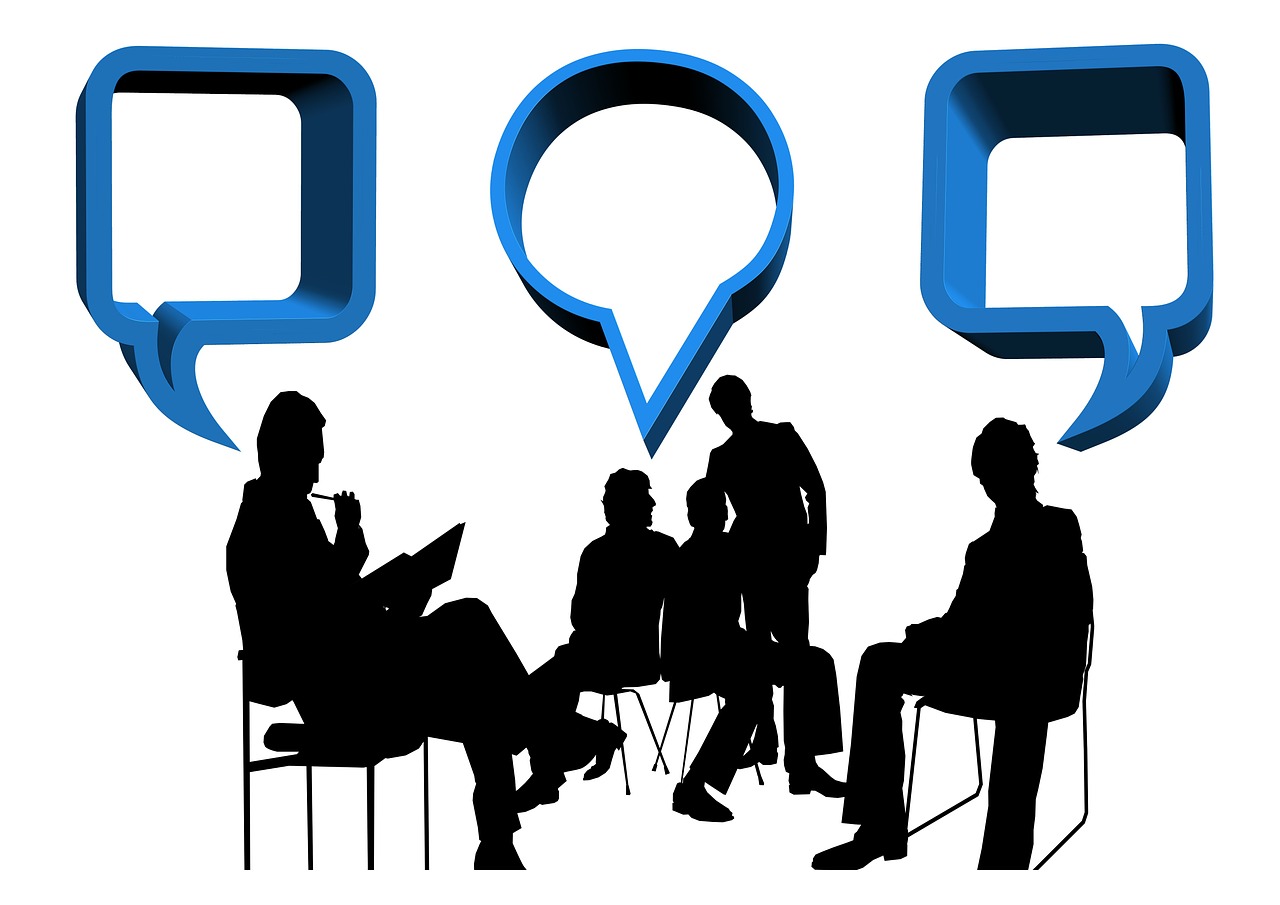 Silhouettes of 4 people sitting in chairs. Word bubbles suggest that they are exchanging ideas.