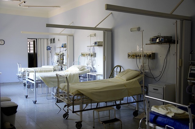 Three empty hospital beds are shown in a dimly lit room.