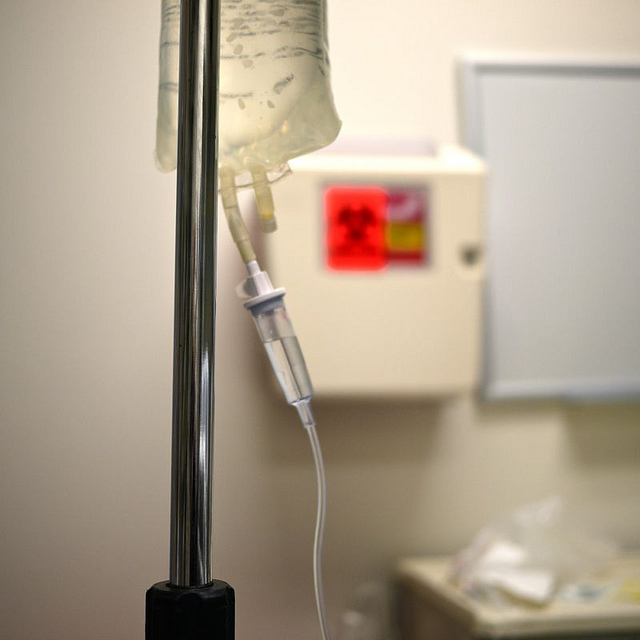 An infusion pump and bag filled with liquid is placed on a stand in a hospital room.