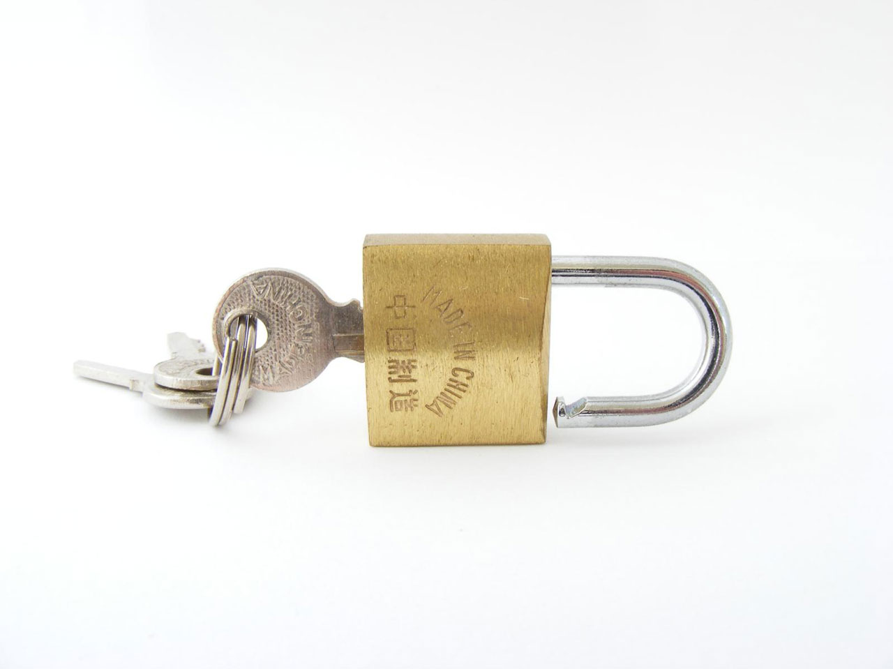 A key is inserted into a gold padlock against a white background.