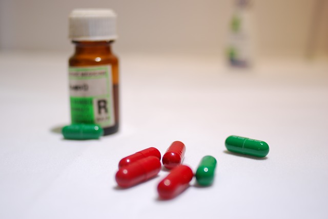Six pills are in focus on a white table. A medicine bottle is blurred in the background.