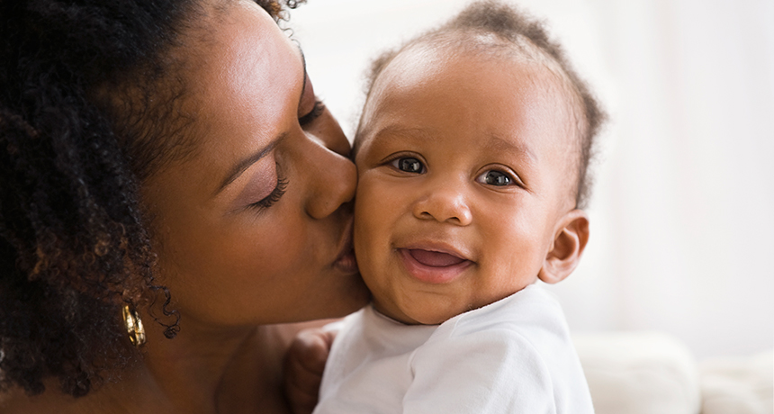 Mother kissing smiling baby on the cheek