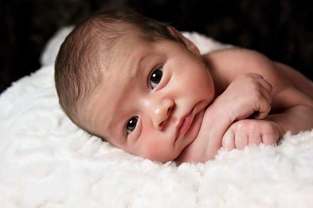 A newborn baby lies on a fluffy white pillow