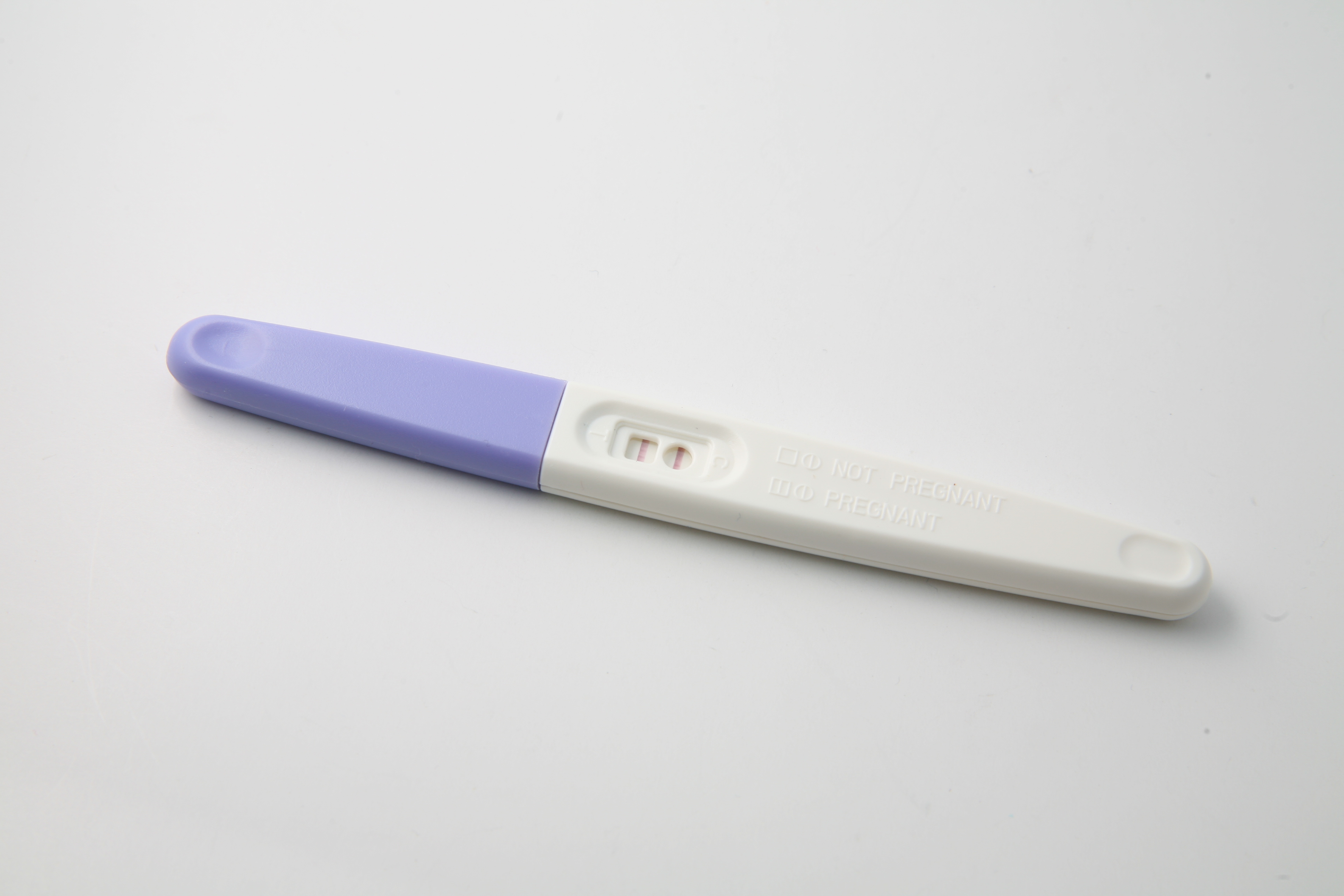 White pregnancy test with a light purple cap on a white background.