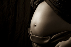 A black and white filtered image of a pregnant stomach exposed.