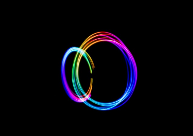 two overlapping rings of rainbow-hued light on a black background