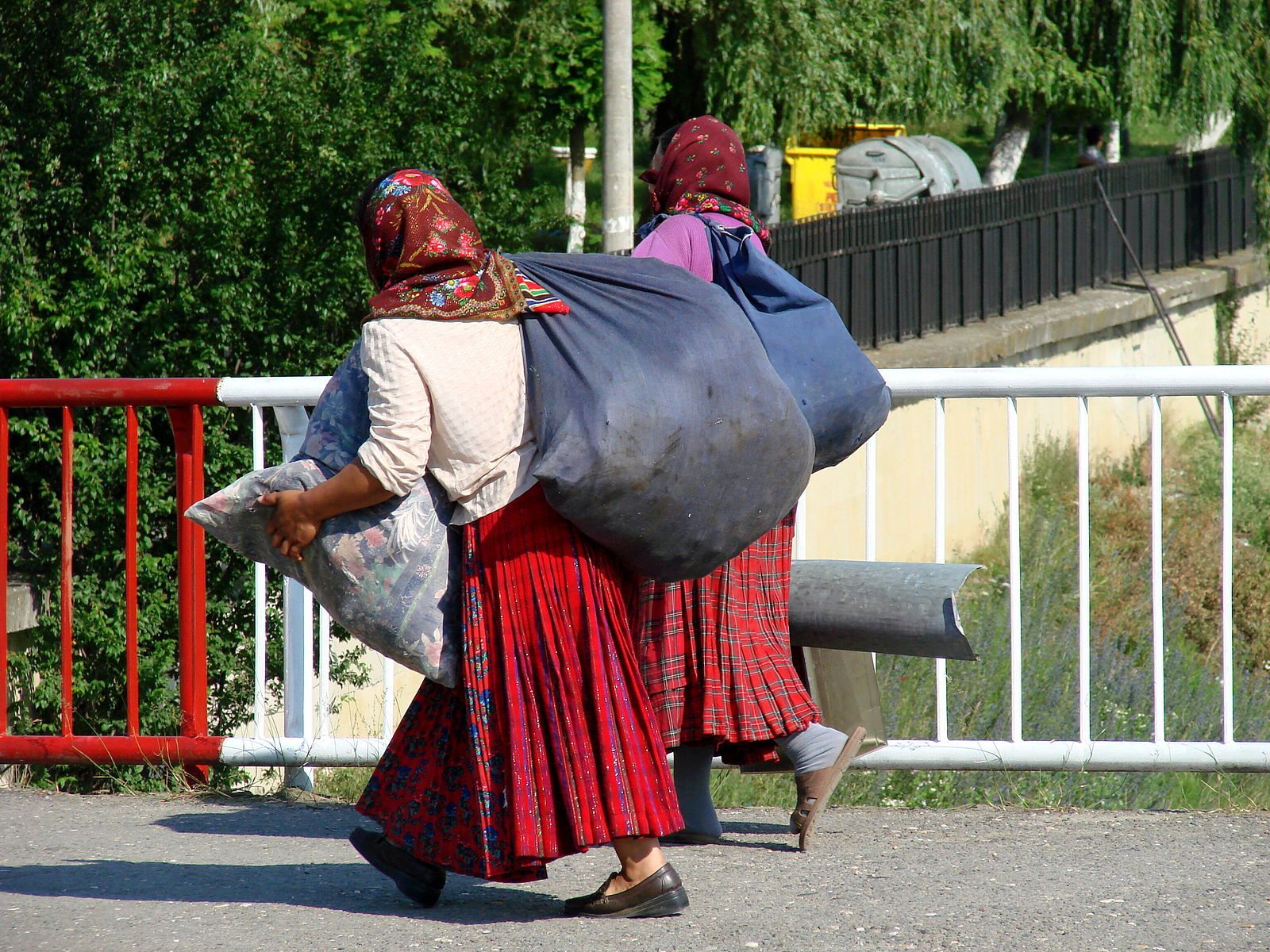 2 Roma women carrying bags