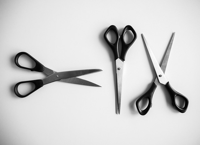 Bird's eye view of three scissors that look the same, lined up on a white table. The two on the sides are slightly opened, while the middle is completely closed.
