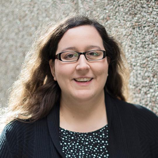 a white woman in glasses smiles for a photo