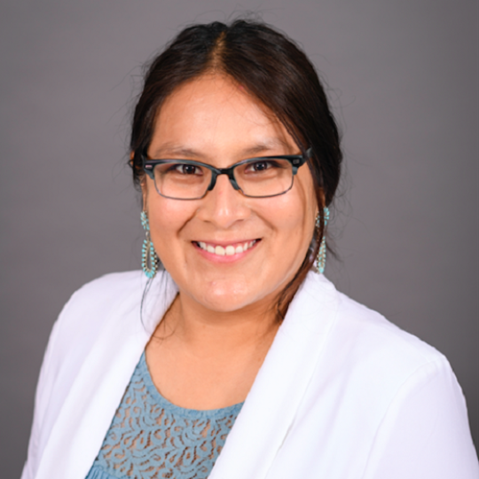 a woman in a white blazer and glasses with dark brown hair