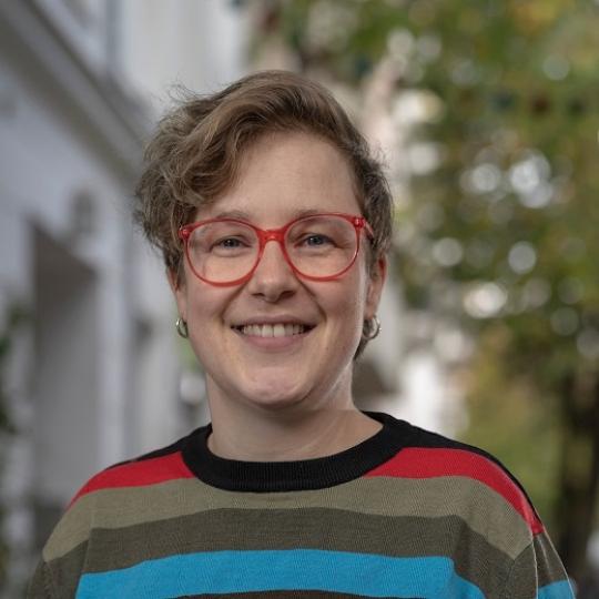 a woman with short hair, red glasses, and a striped shirt