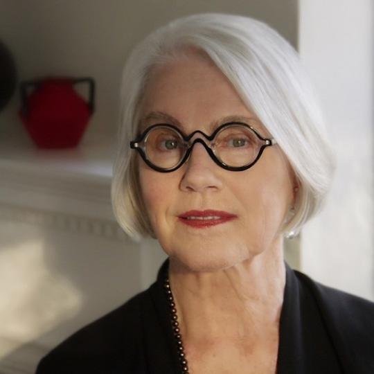a white woman with white hair and black glasses