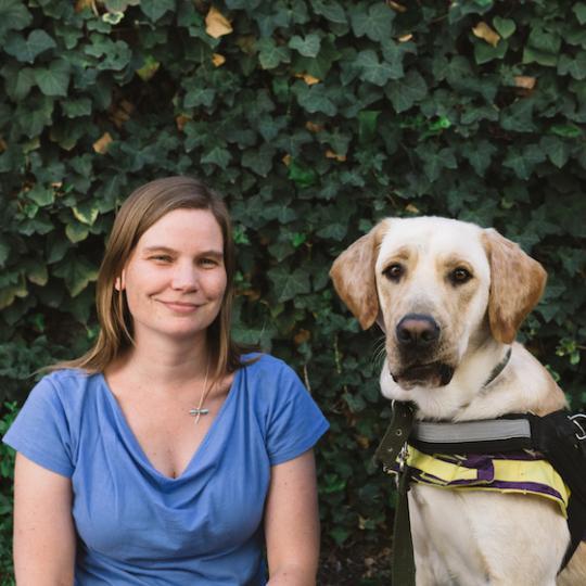 a white woman with blond hair in a blue shirt and a golden haired dog