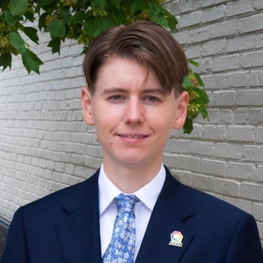 a white person with short brown hair wearing a tie and blue suit