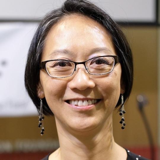 an Asian woman with glasses and short black hair smiles