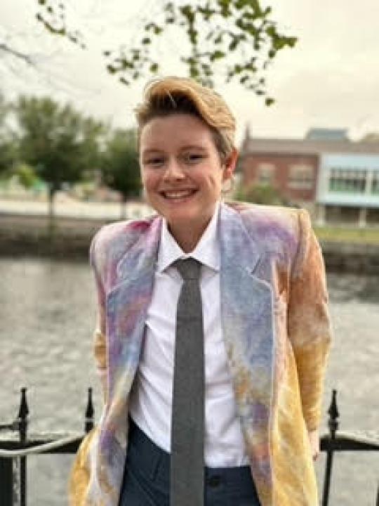 A white person with short light brown hair wearing a tie and colorful blazer