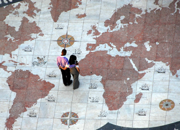 A heternormative couple looks down at the ground, which features a world map of 7 continents.