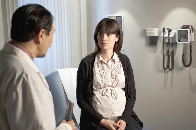 Doctor speaking to pregnant woman in exam room